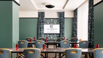 A conference room with a long table, multiple chairs, and red cups. A sign above the table reads "The Candler Hotel."