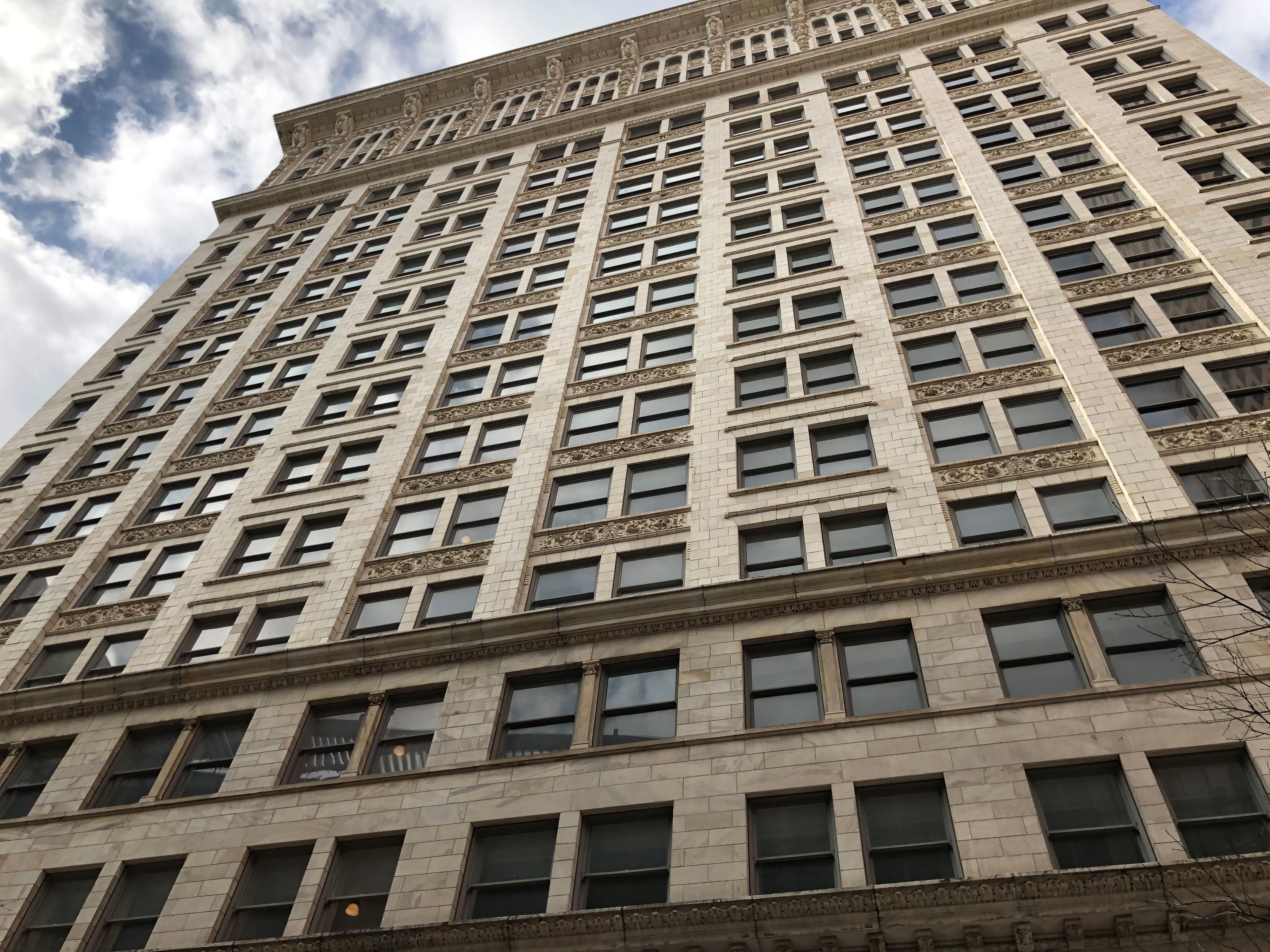 Un edificio alto de varios pisos con fachada simétrica, ventanas distribuidas uniformemente y detalles de cantería decorativa.