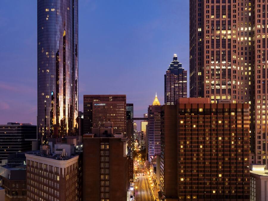 A cityscape at dusk with illuminated skyscrapers and a clear view of the streets.
