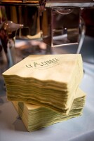 A stack of neatly folded napkins with the text "LYA FORCE" on them, placed on a table.