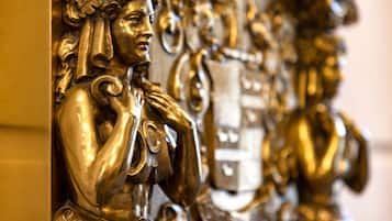 Primer plano de una estatua dorada con detalles intrincados y una jarrón.