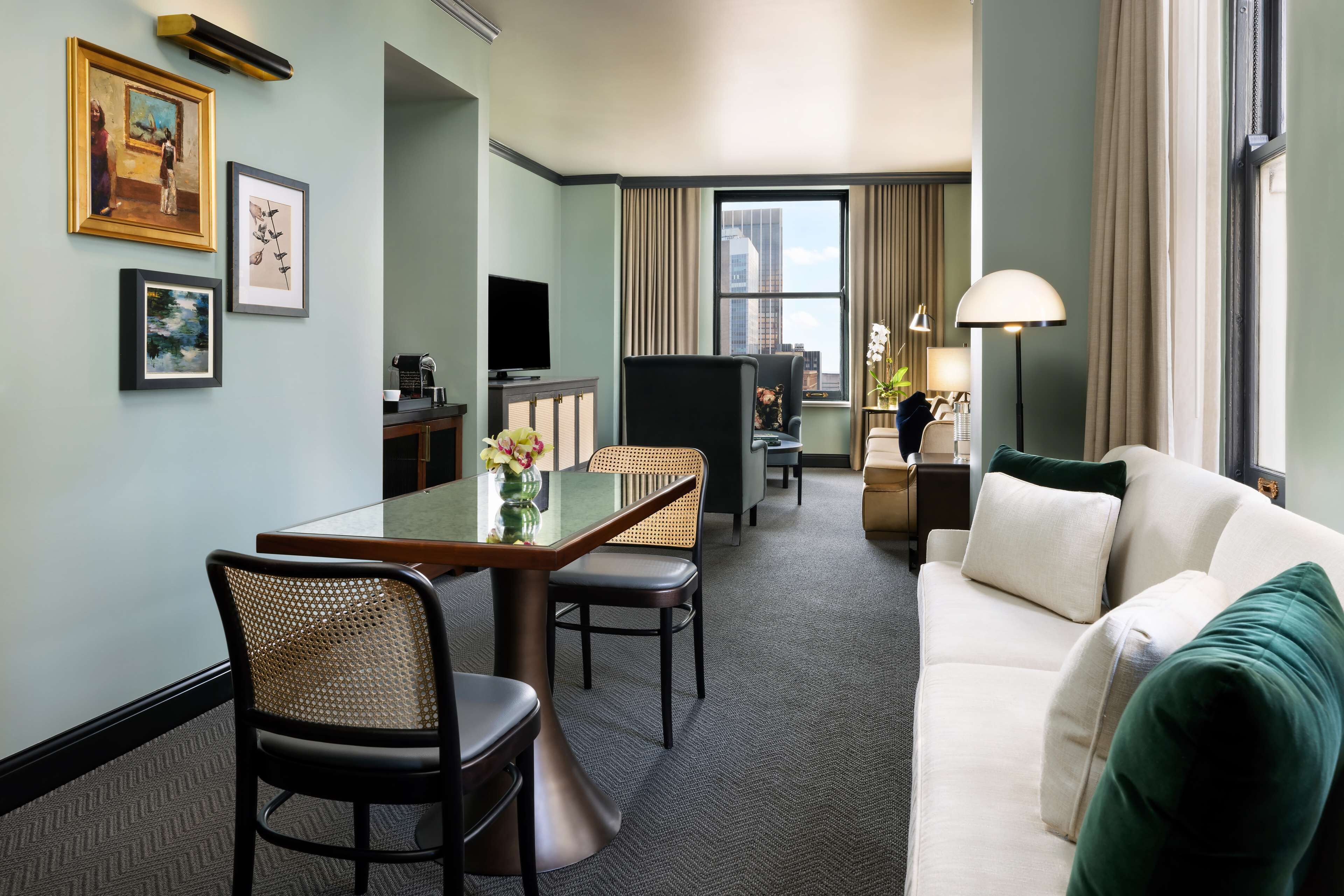 A hotel room with a dining area, a sofa, and a TV.