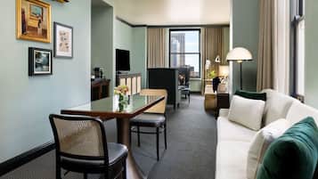 A hotel room with a dining area, a sofa, and a TV.