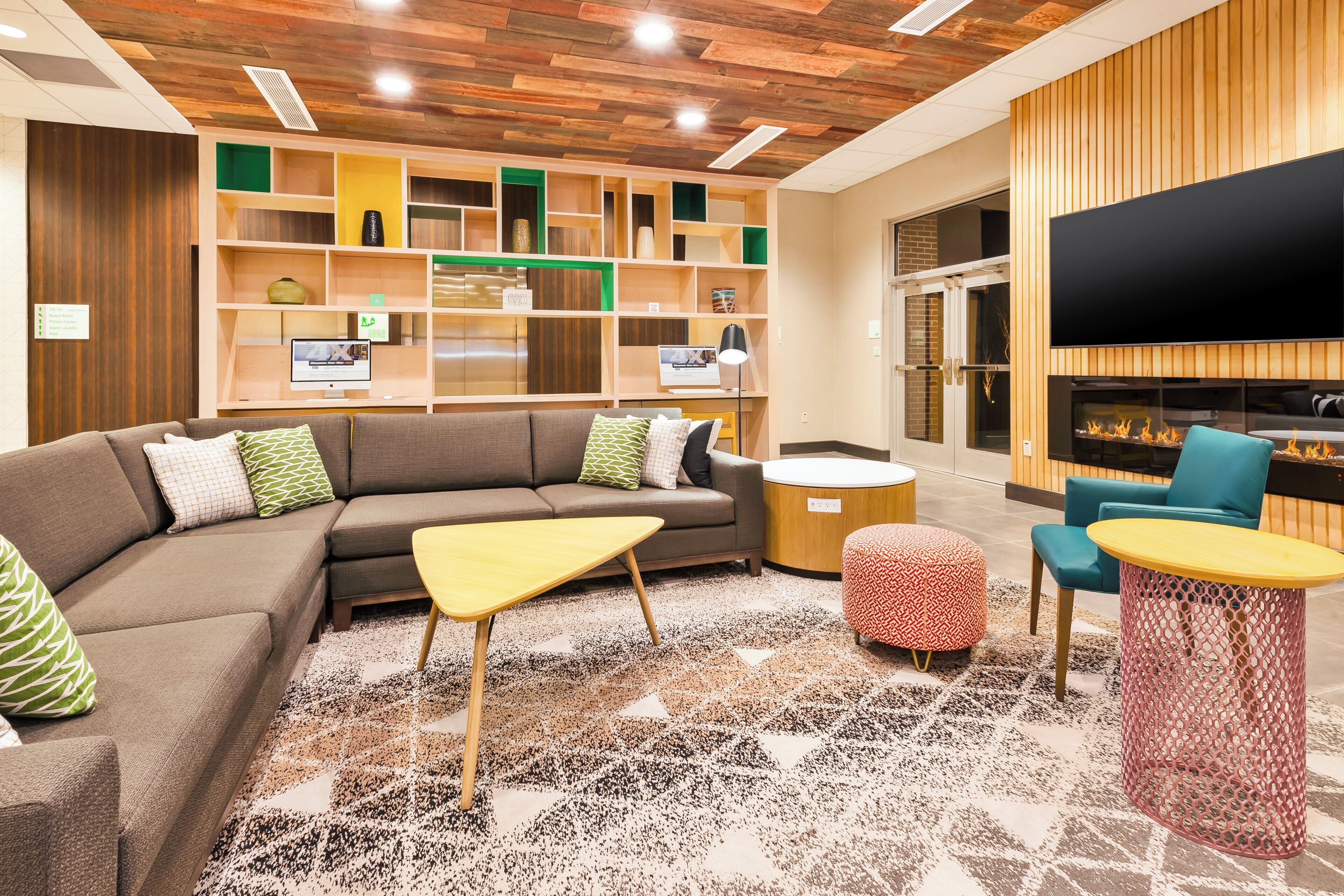 A modern living room with a sectional sofa, a coffee table, ottomans, and a fireplace.