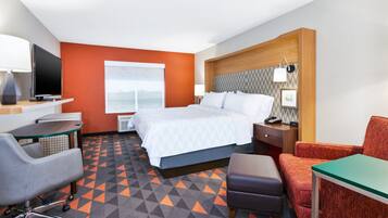 A hotel room with a bed, a desk with a computer, a chair, and a TV.