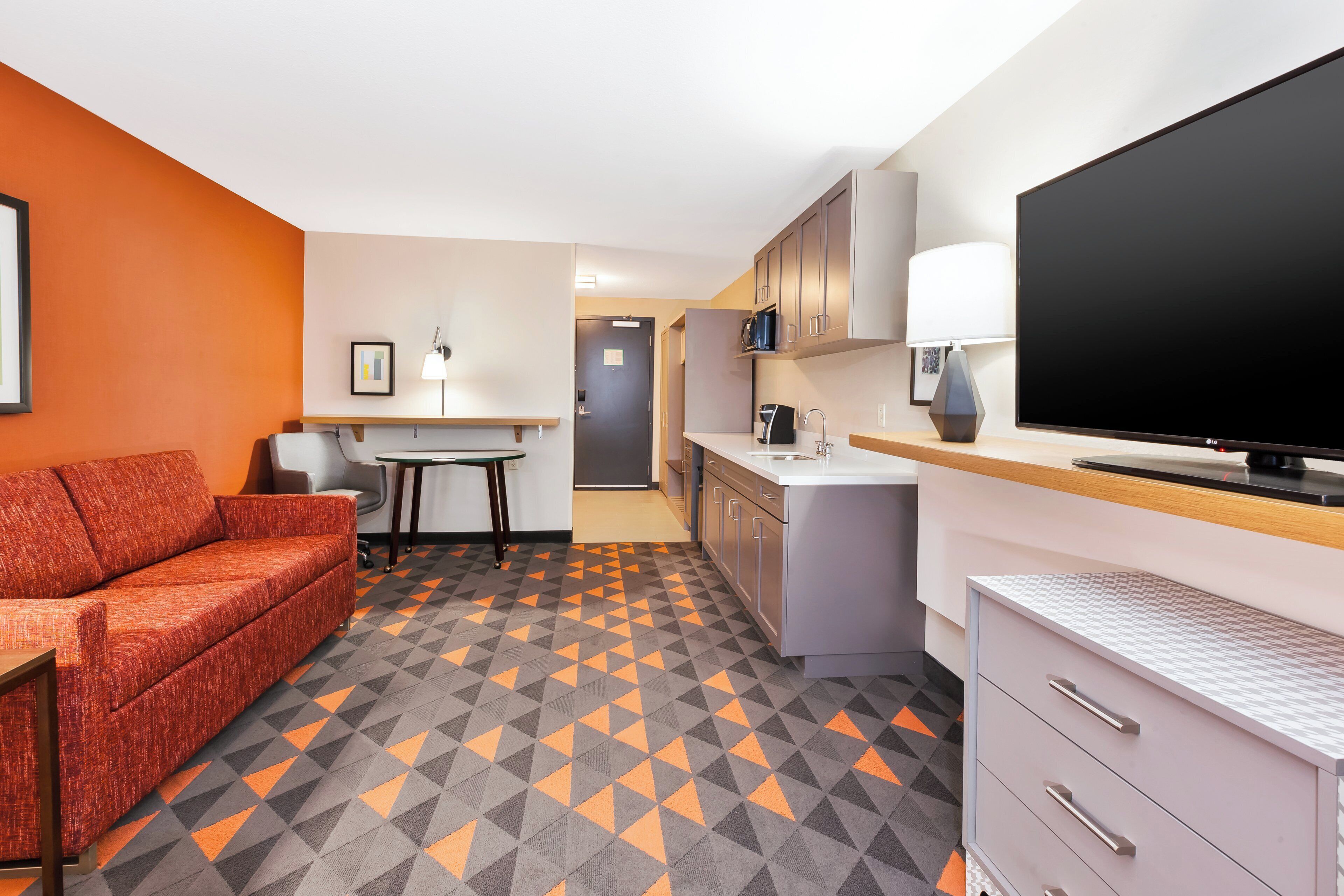 Et stilfuldt hotelværelse med sofa, spisebord, tekøkken og fladskærms-tv.