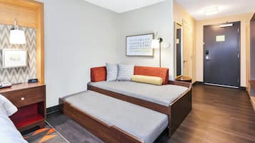 A room with a bed, bedside table, lamp, framed picture, and a door.