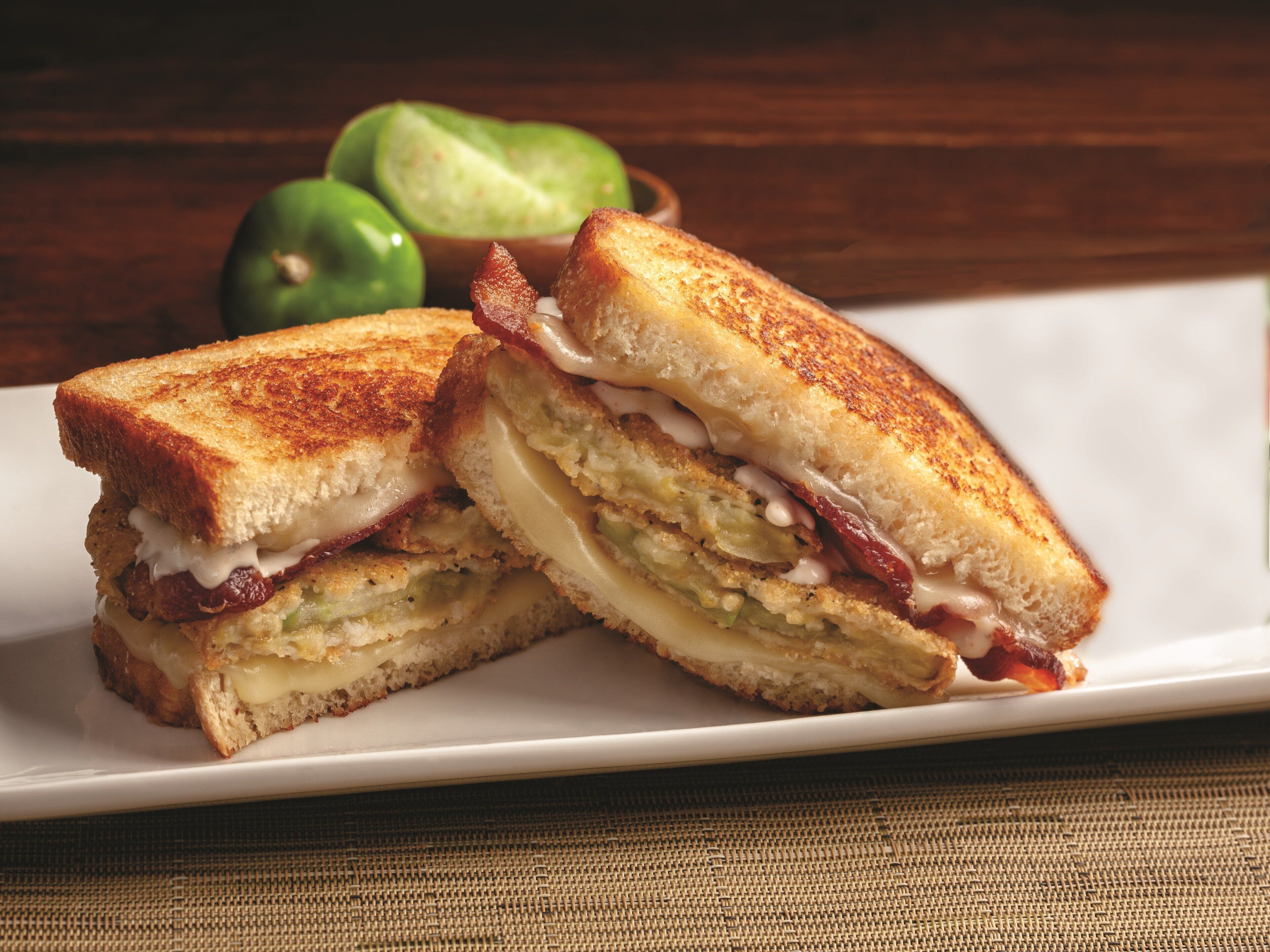 A grilled sandwich cut in half, placed on a white plate.