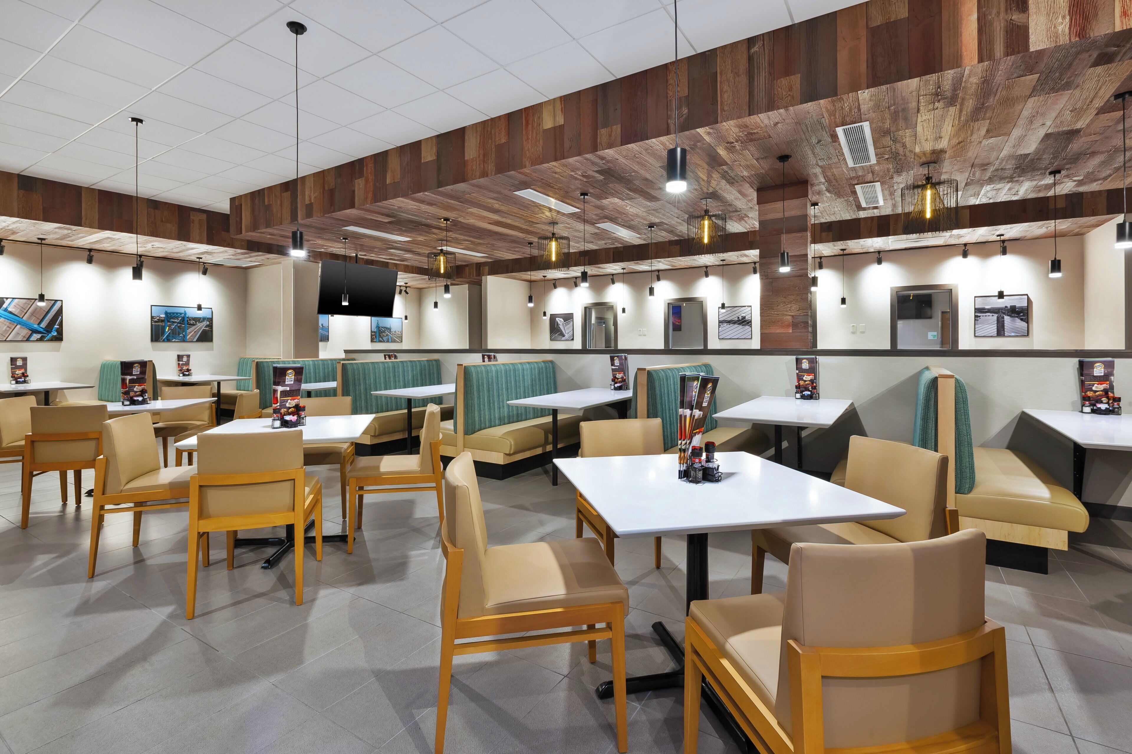 A restaurant with booths and tables, wooden ceiling, and artwork on the walls.