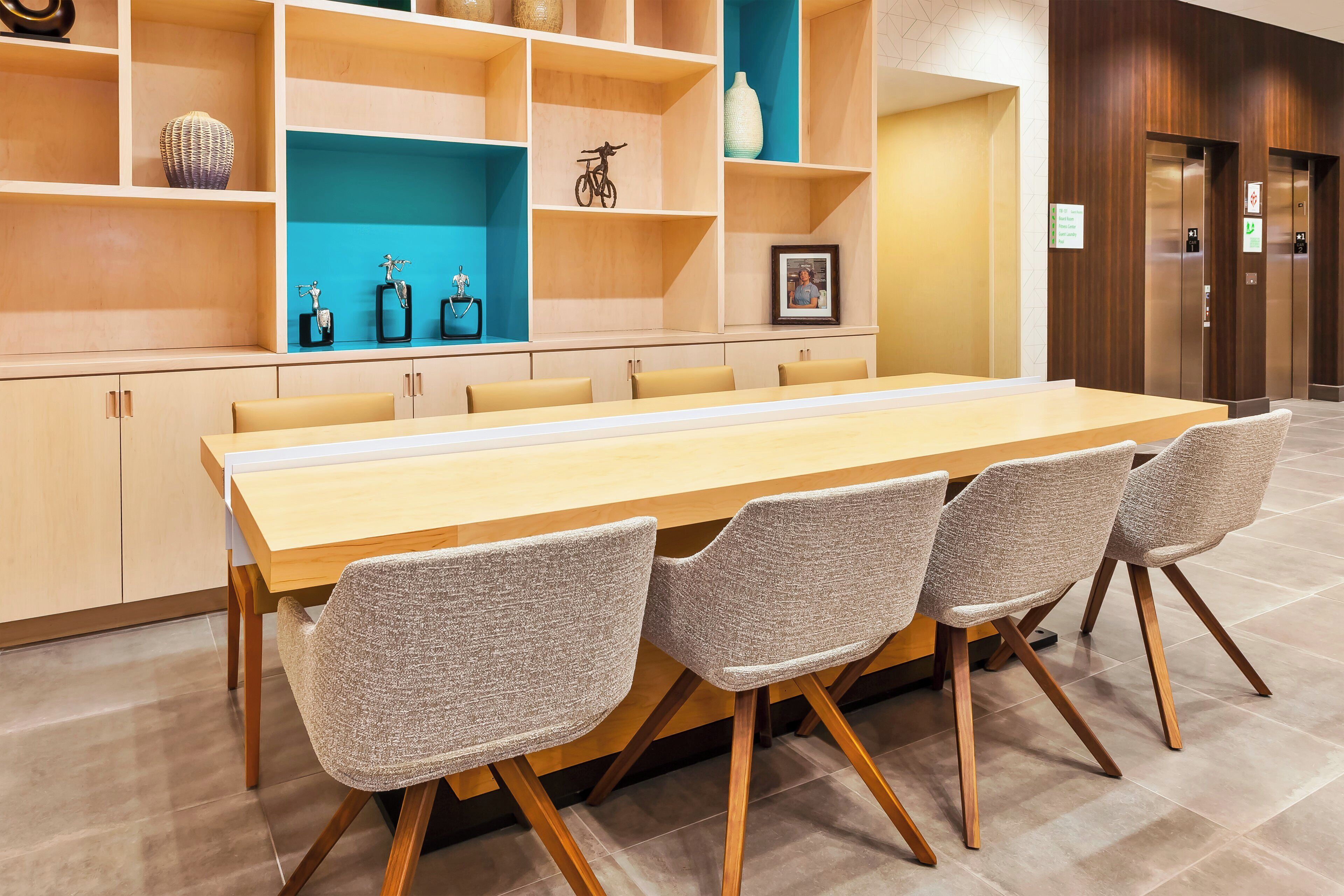 Un salón de conferencias con una mesa larga, cuatro sillas y una pared decorada en azul.