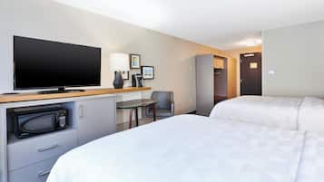 A hotel room with a bed, a desk with a television, a microwave, a chair, and a wardrobe.