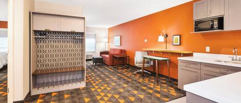 Habitación de hotel con kitchenette, zona de estar con sofá y sillones, y piso estampado.