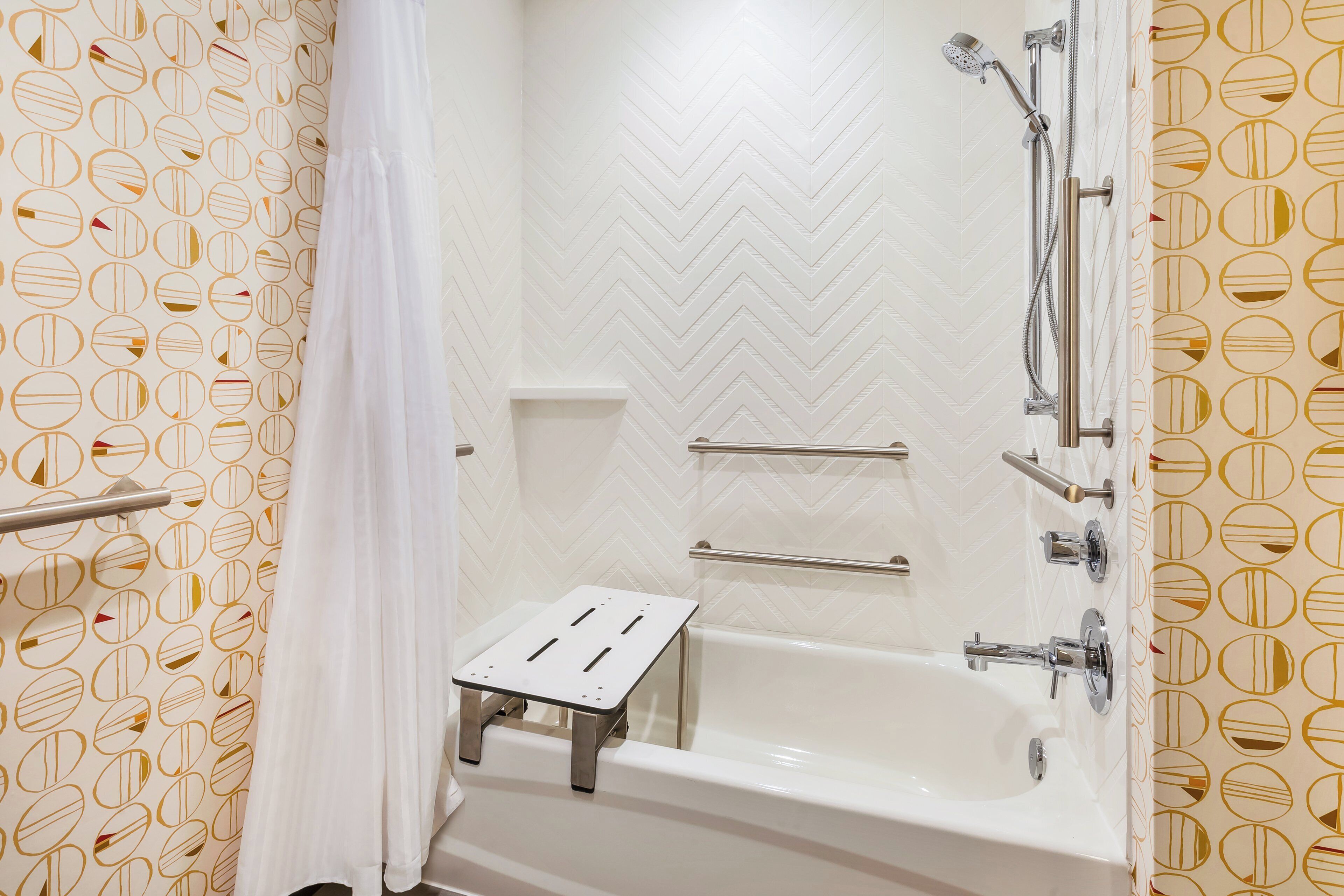 A bathroom with a white bathtub, shower, and a small step stool.