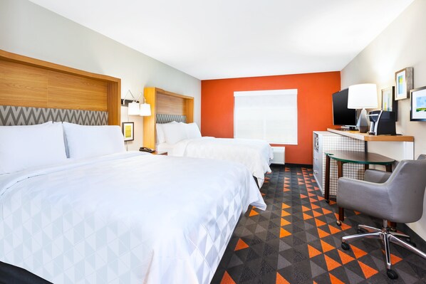 A hotel room with two beds, a desk with a computer, a chair, and a television.