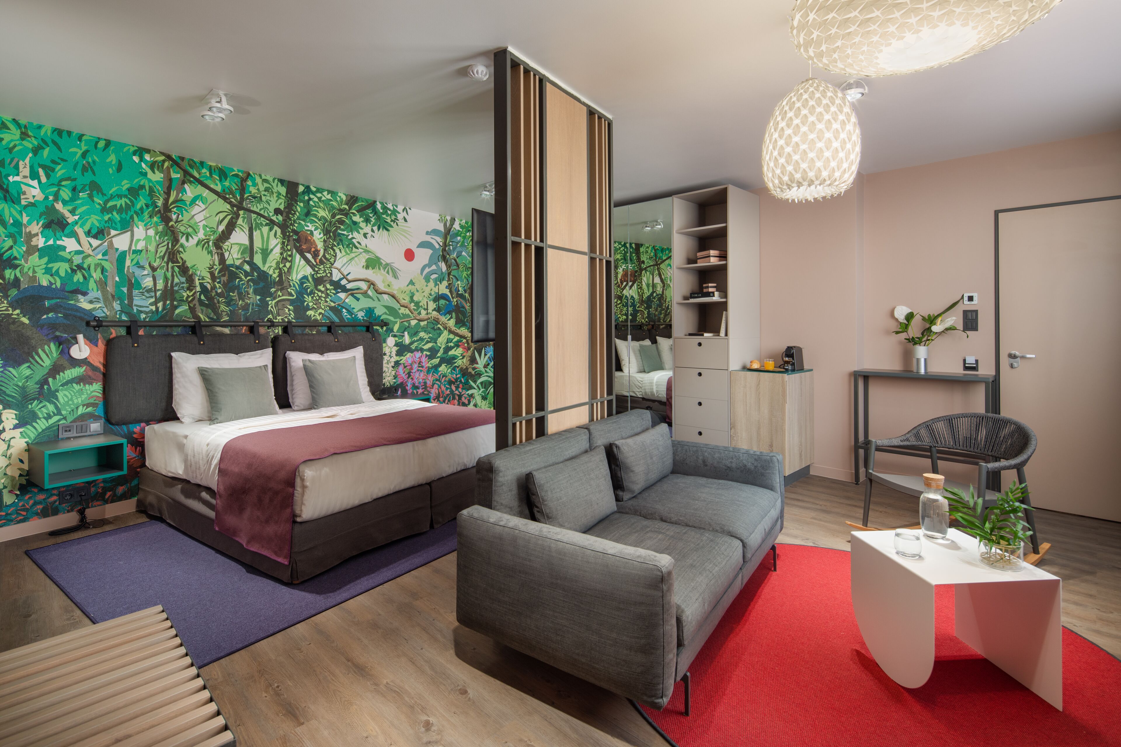 A modern bedroom with a bed, sofa, and a large mural on the wall.