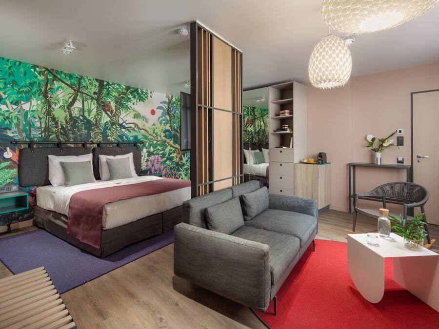 A modern bedroom with a bed, sofa, and a large mural on the wall.