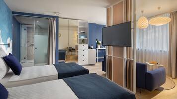 Una habitación de hotel moderna con dos camas, televisión, escritorio y zona de ducha.