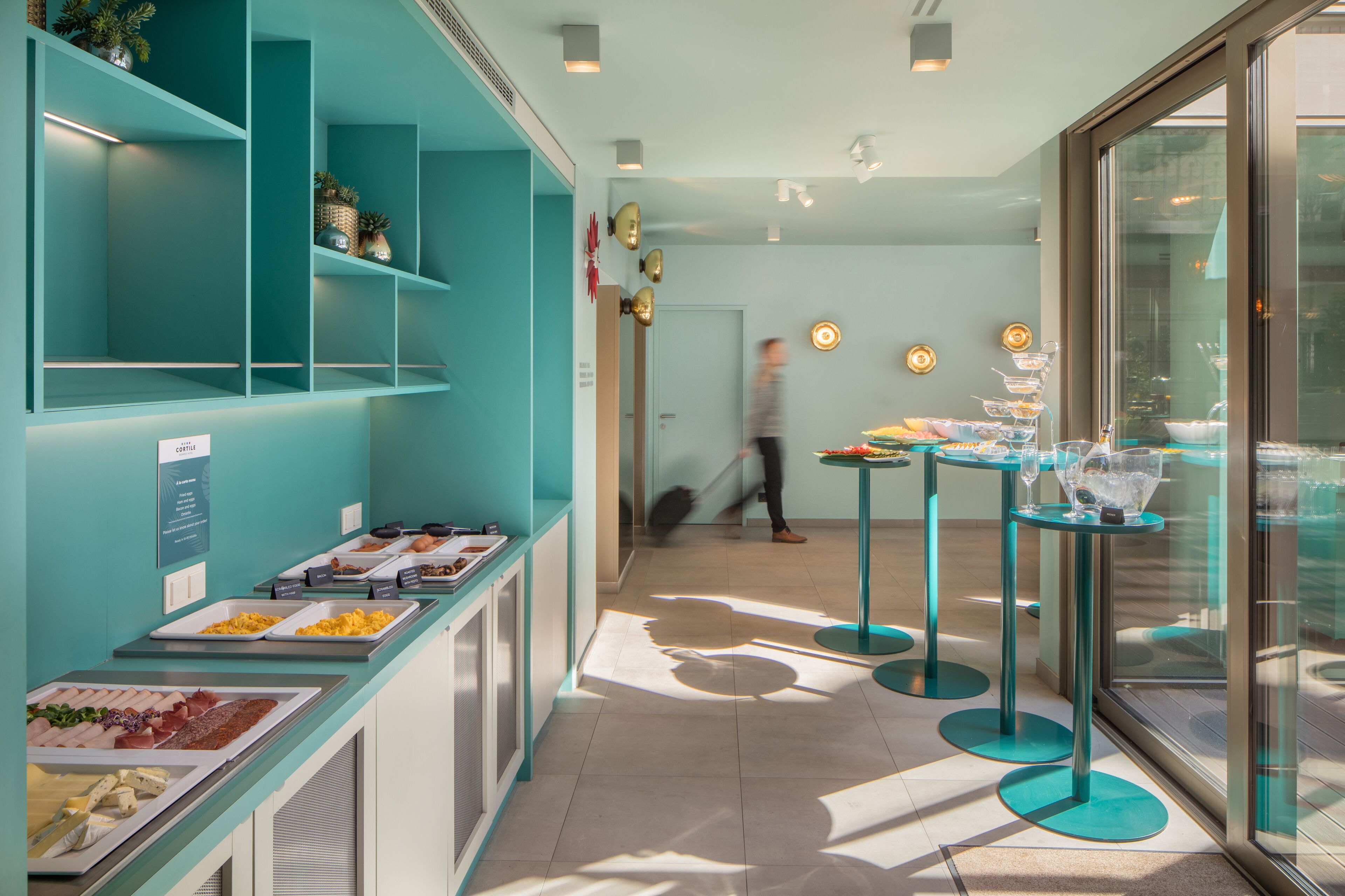 A buffet area with various food options and a glass-enclosed dining area with tables and chairs.