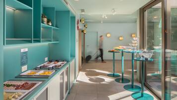 A buffet area with various food options and a glass-enclosed dining area with tables and chairs.