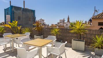 Un patio al aire libre con mobiliario de mimbre blanco y plantas en macetas.