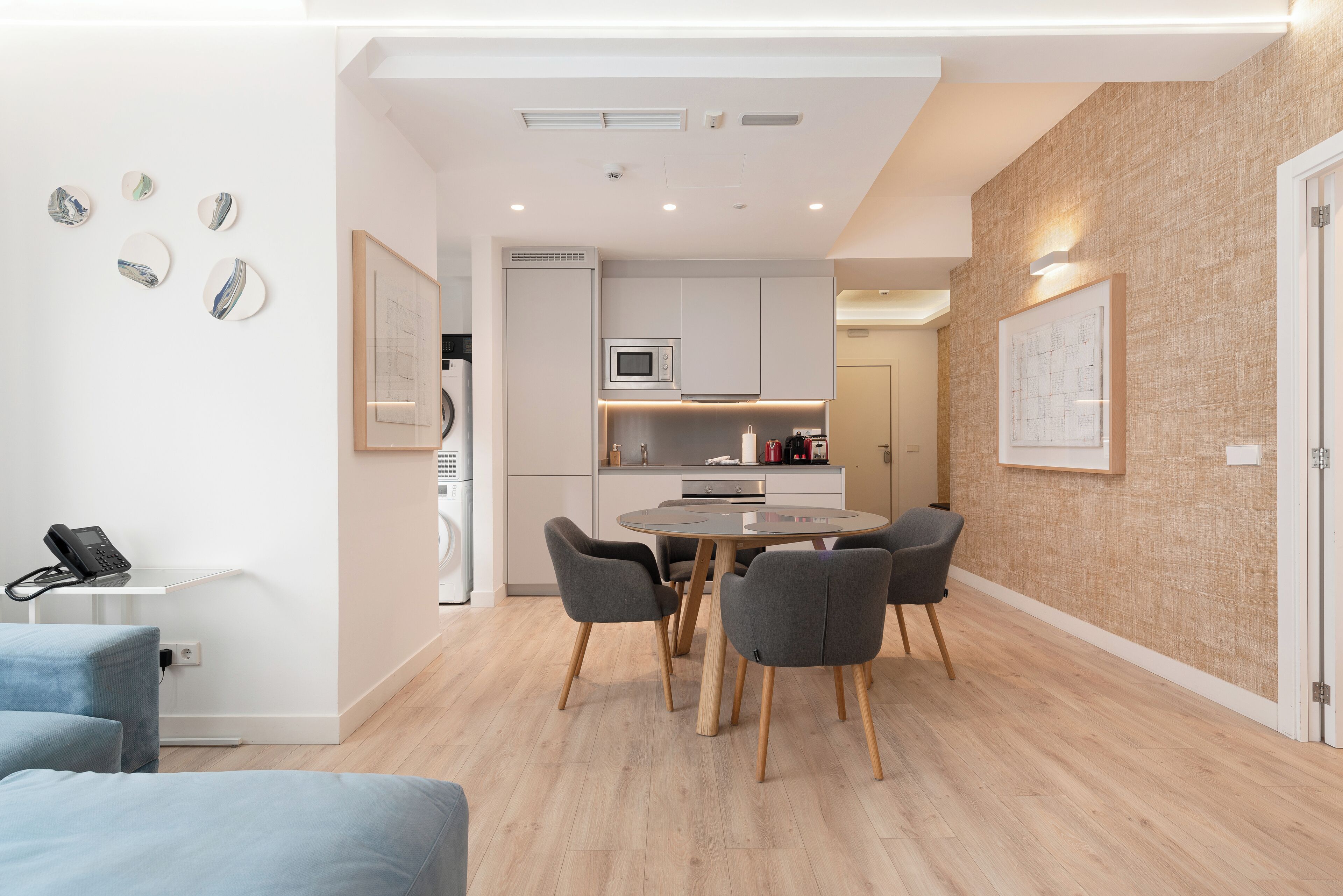 A modern kitchen with white cabinets, a microwave, and a dining area with a round table and four chairs.