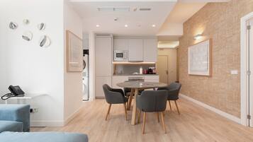 A modern kitchen with white cabinets, a microwave, and a dining area with a round table and four chairs.