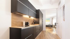 Een moderne keuken met donkere kastjes, een houten aanrechtblad en een inbouwoven.