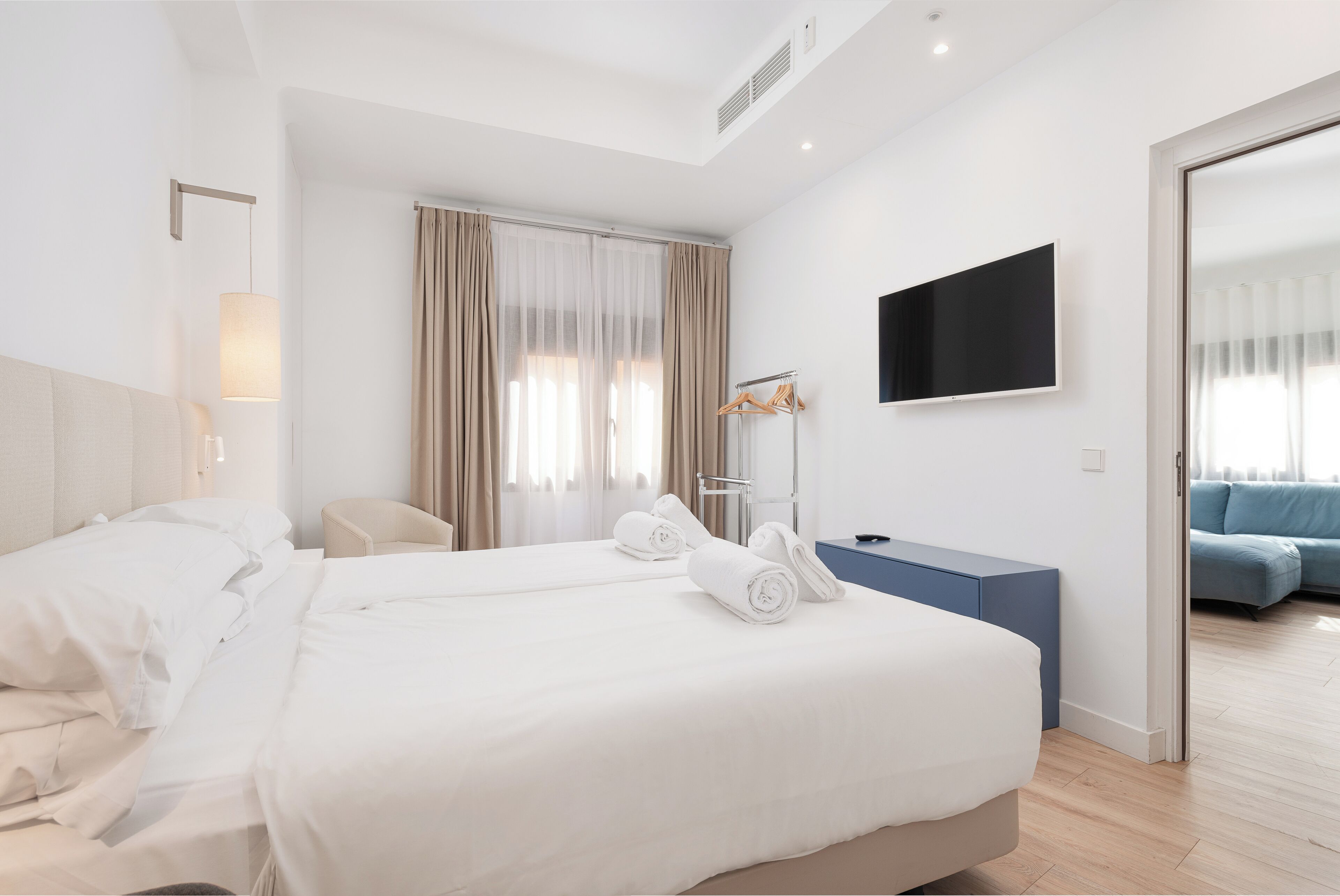 A hotel room with two beds, a TV, a desk, and a seating area.