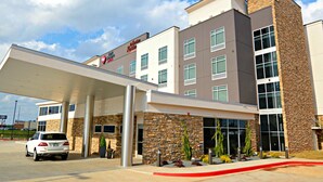 A modern hotel with a covered entrance, multiple windows, and a stone facade.