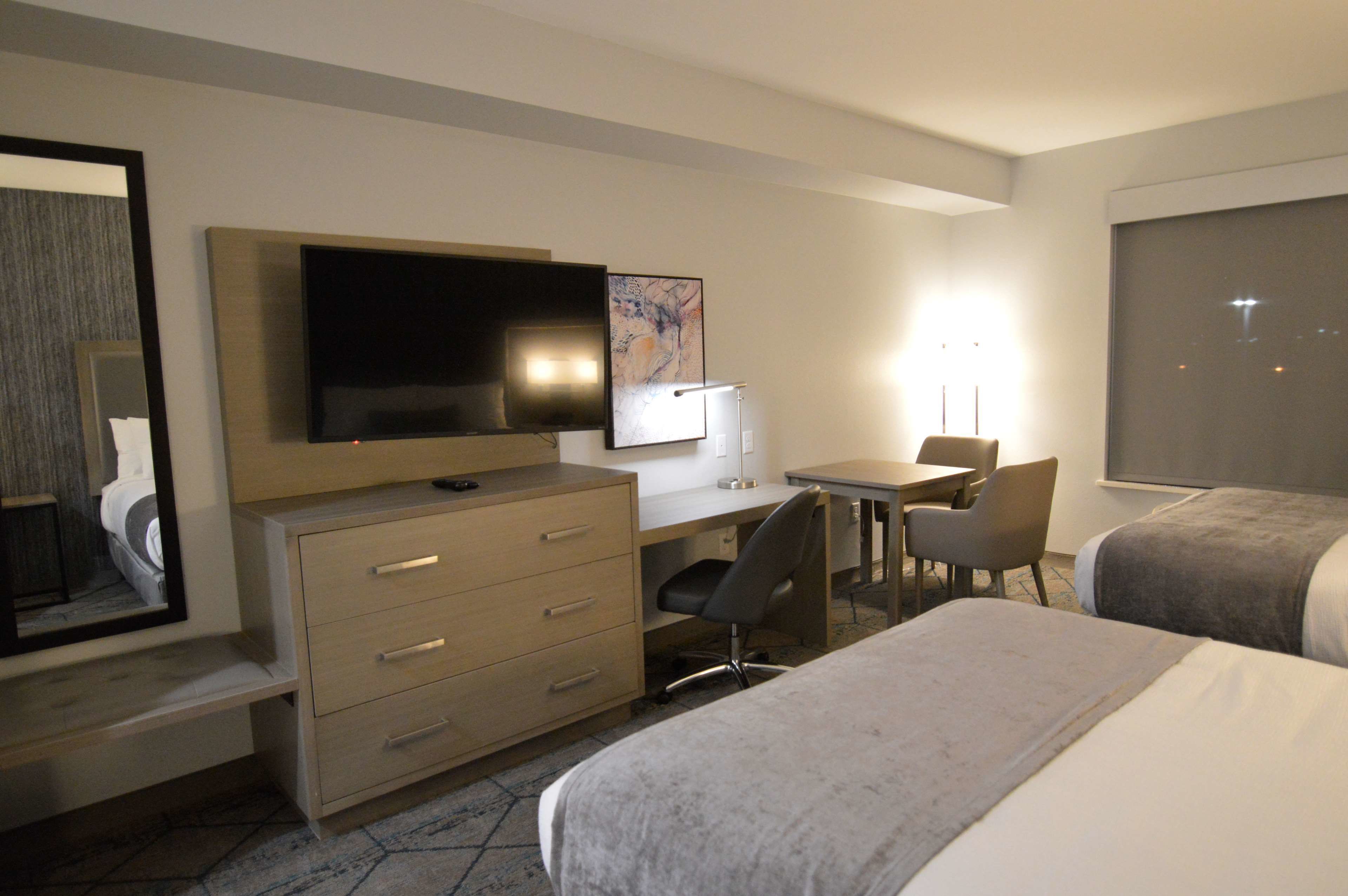 Une chambre d’hôtel équipée d’un lit, d’un bureau, d’une chaise, d’une télévision et d’une grande fenêtre.