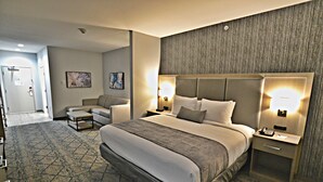 A hotel room with a large bed, two bedside tables, a sofa, and a patterned carpet.