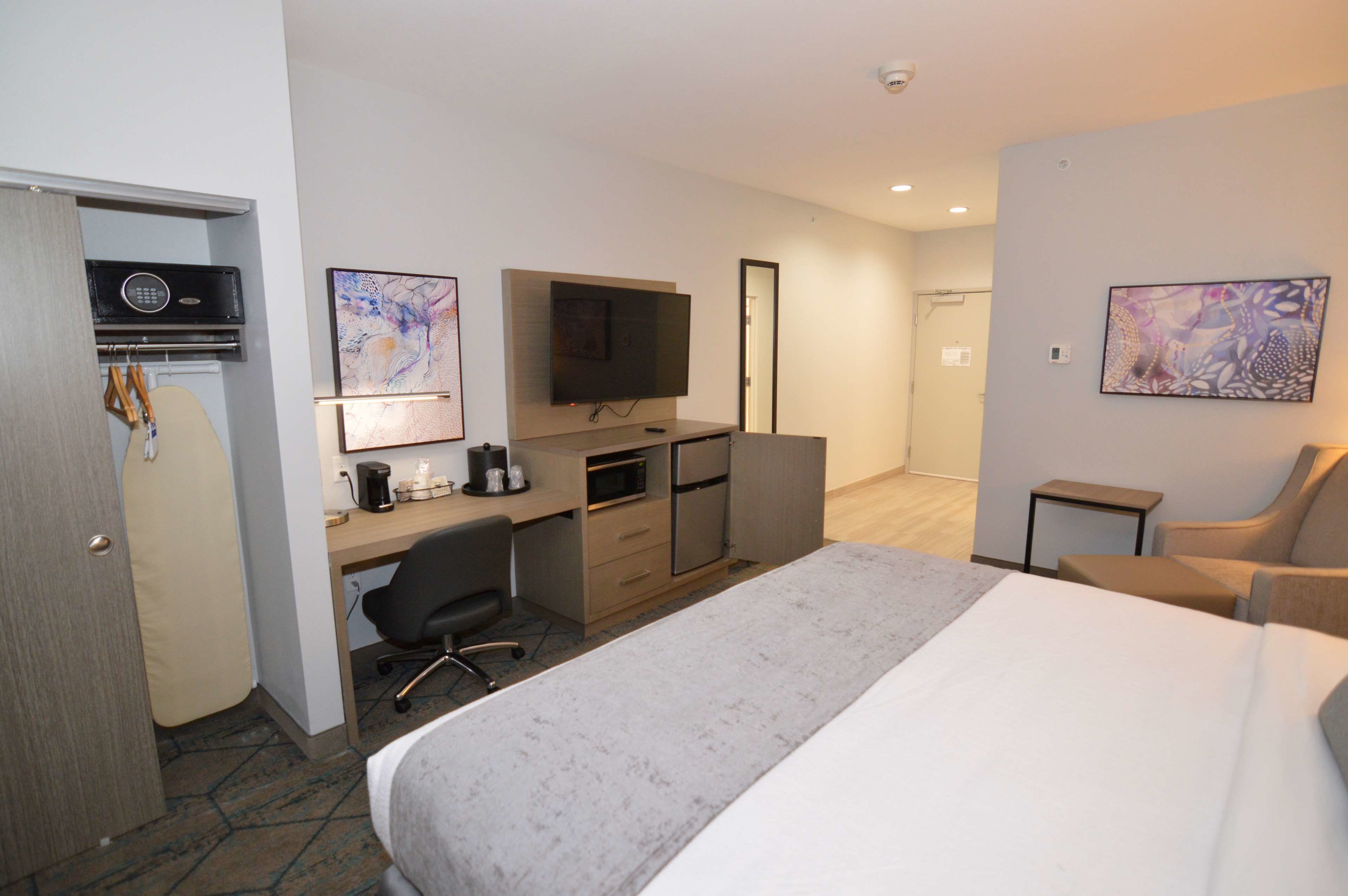 A hotel room with a large bed, a desk with a computer, a television, and a chair.
