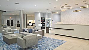 A modern lobby with sofas, a reception desk, and a patterned carpet.