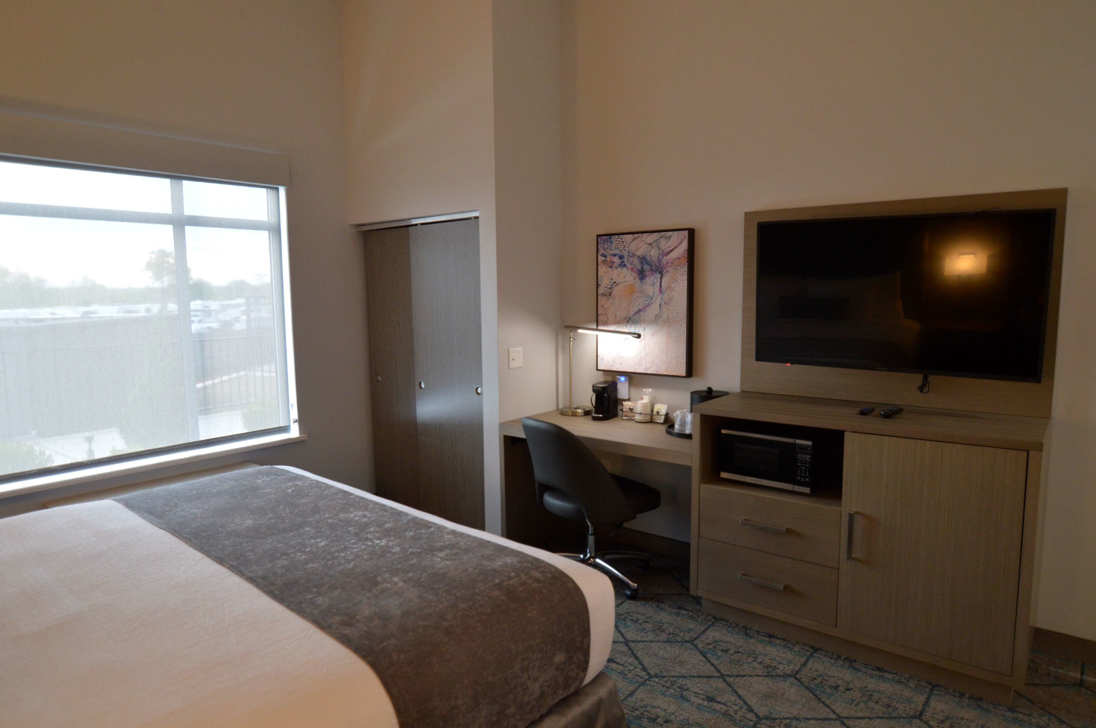 Une chambre d’hôtel équipée d’un lit, d’un bureau, d’une chaise, d’une télévision, d’un four à micro-ondes et d’une armoire.