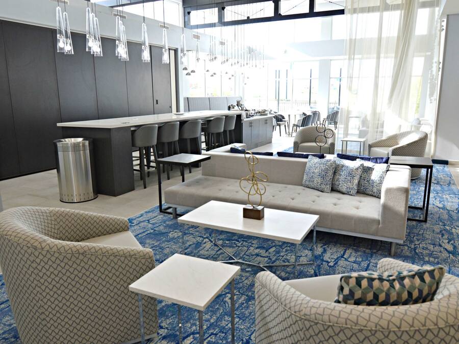 Un hall d’hôtel moderne doté d’un bar, d’un espace salon et de grandes fenêtres.