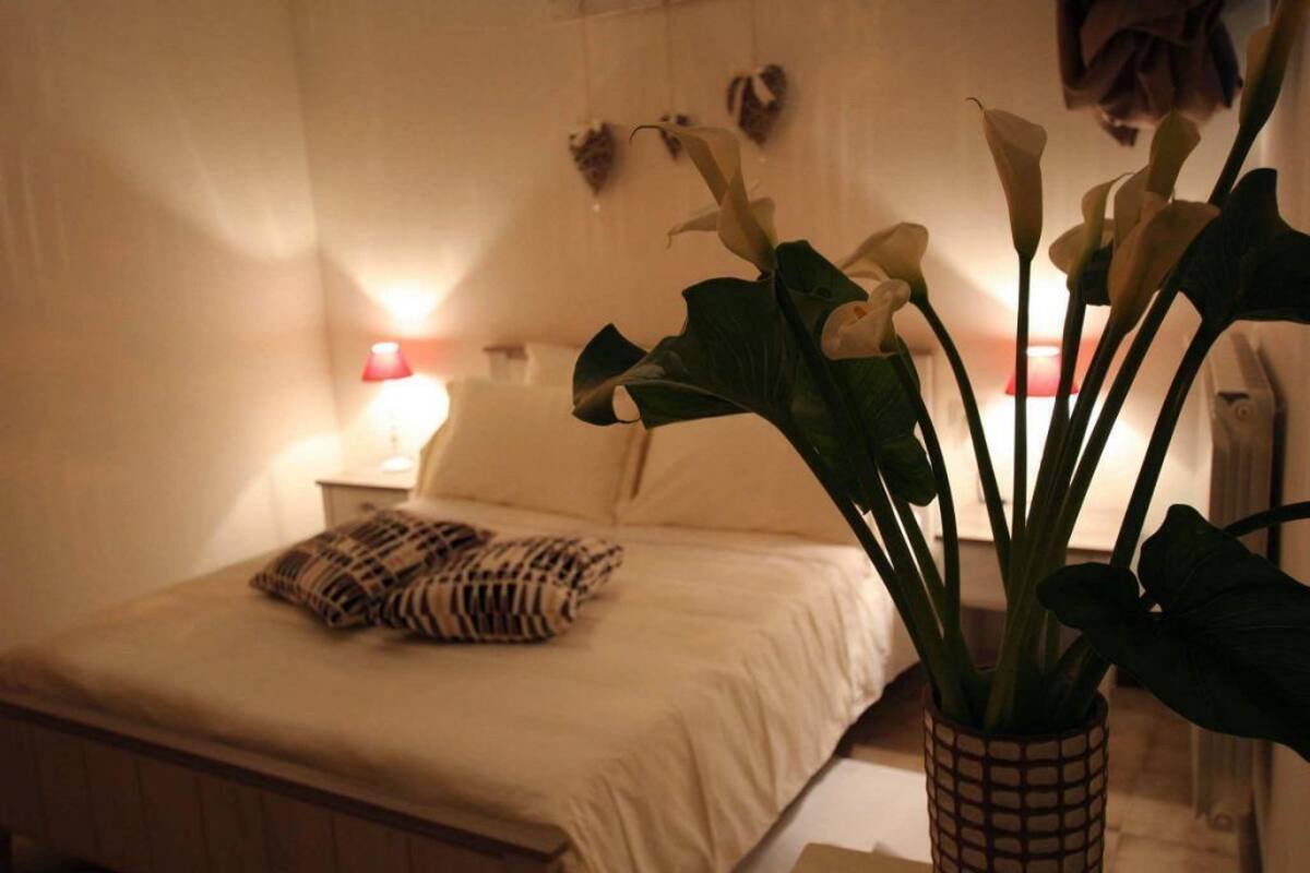 A bedroom with a bed, a bedside lamp, a potted plant, and a wall-mounted heart decoration.