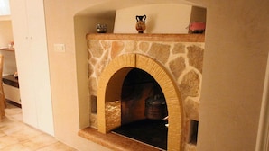 A stone fireplace with an arched opening, a tiled floor, and a small shelf above it. - Suite del Vico Family (Alberobello)