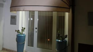 A white building with a covered entrance, two potted plants, and a tiled floor. - Suite del Vico Family (Alberobello)