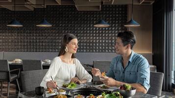 A modern dining area with a black grill table, various dishes, and two people dining.