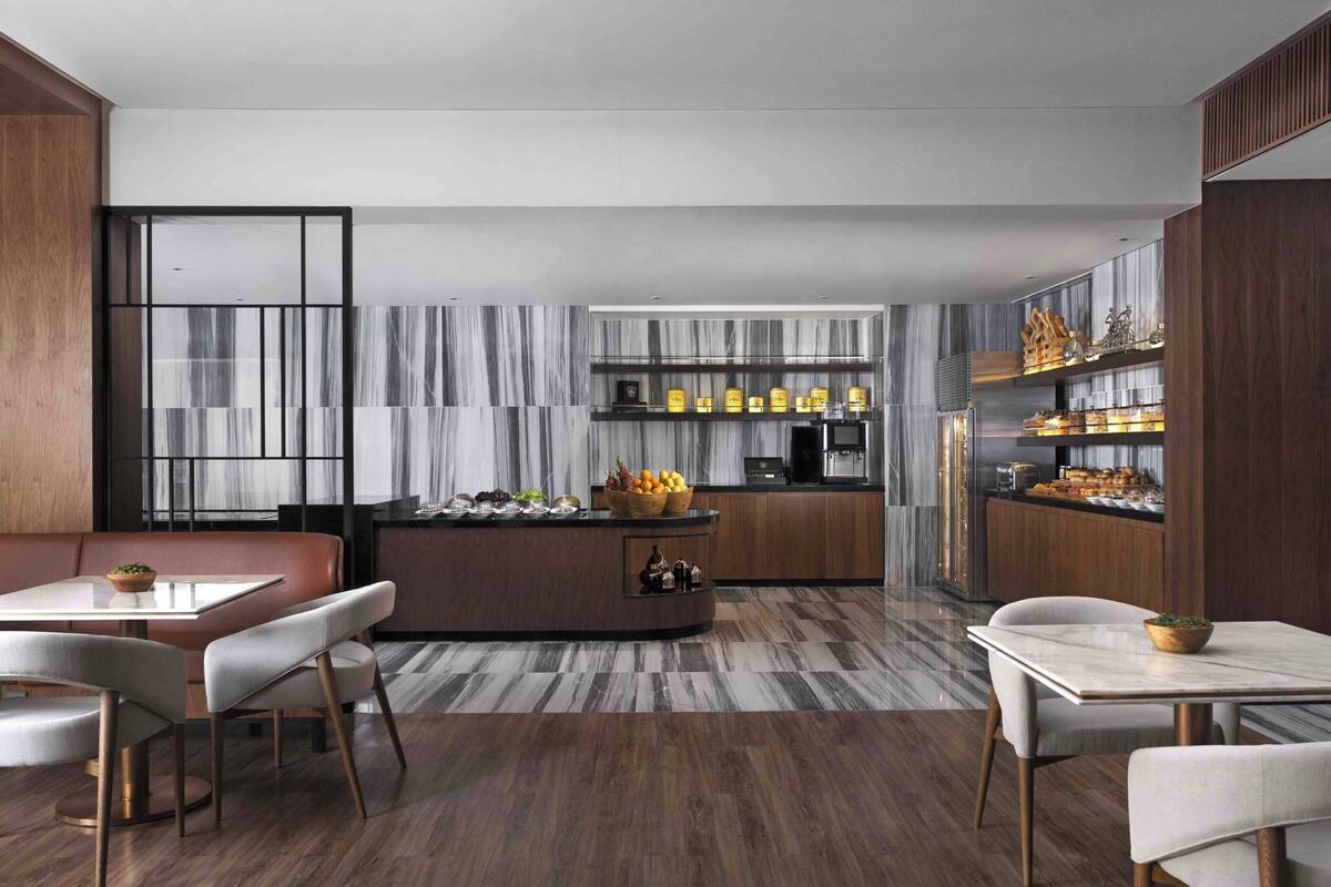 A modern kitchen with a central island, built-in cabinets, and a marble backsplash.