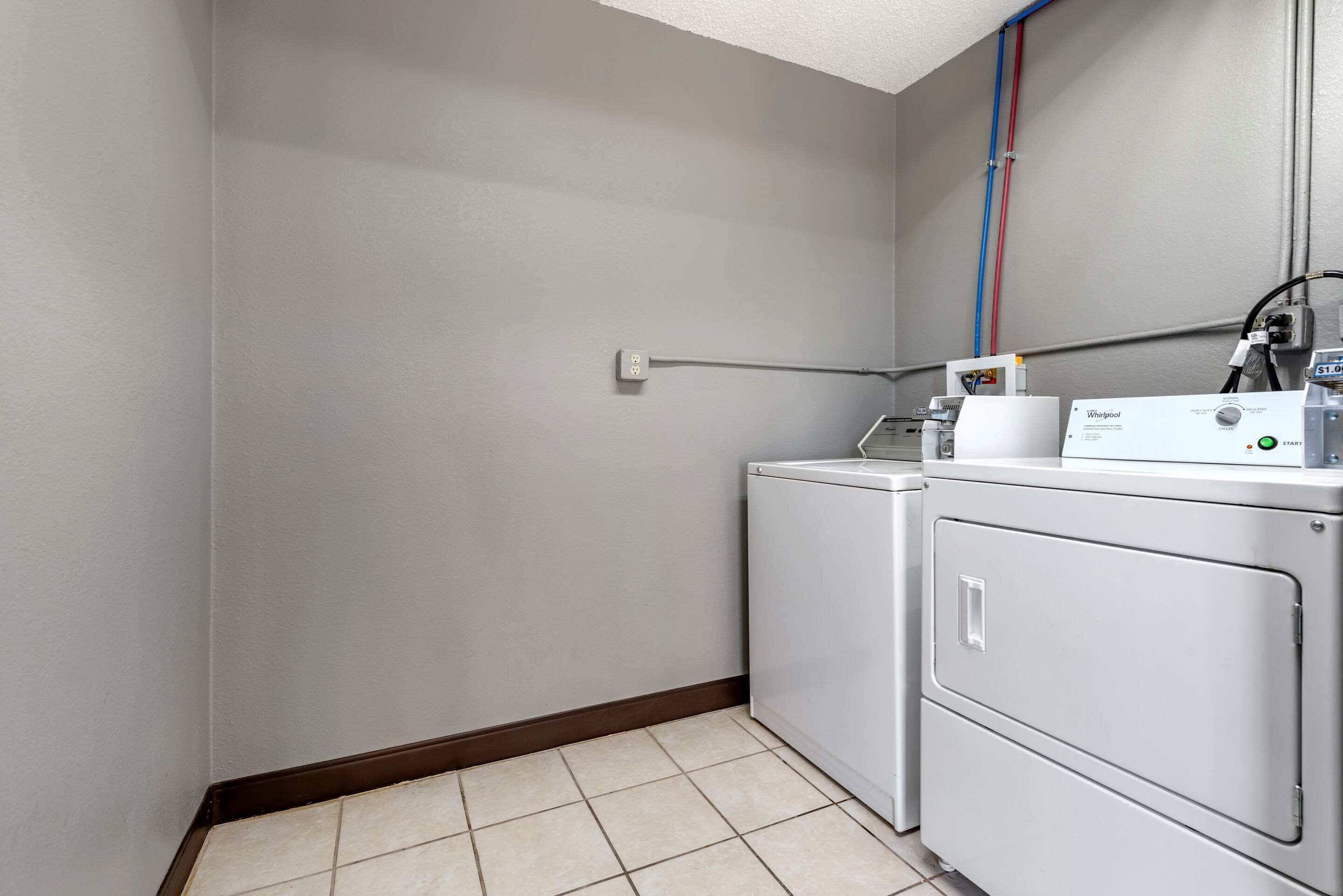 Un lavadero con lavadora, secadora y panel de control.