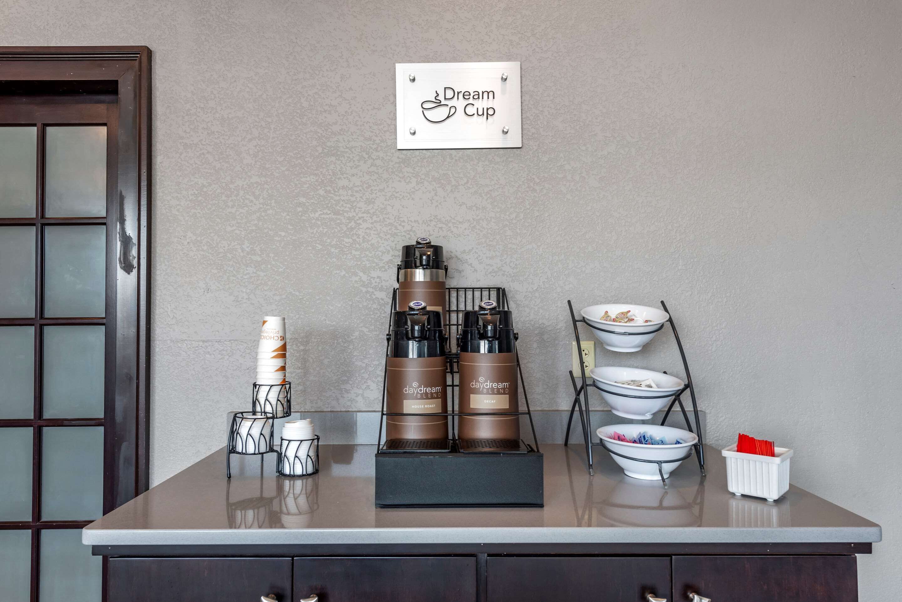 A coffee station with a coffee machine, cups, and a sign that reads "Dream Cup".