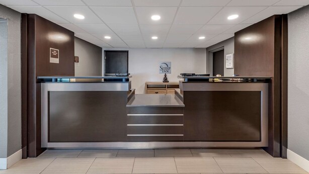 A reception area with a modern design, featuring a central counter, a reception desk, and a sign that reads "Sleep Inn." - Sleep Inn Terre Haute University Area (Terre Haute)