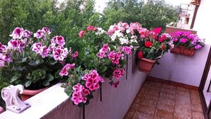 A balcony with potted geraniums and a white sculpture. - B&B Casa Mia (Alghero)