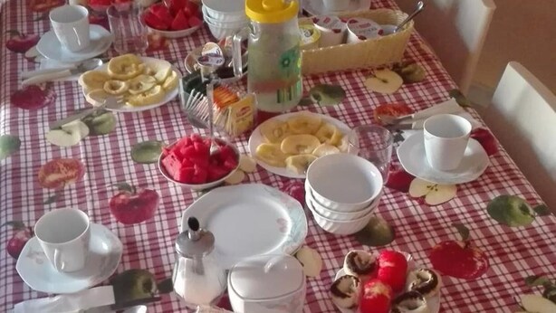 A dining table set with plates, cups, and various food items, covered with a checkered tablecloth. - B&B Casa Mia (Alghero)