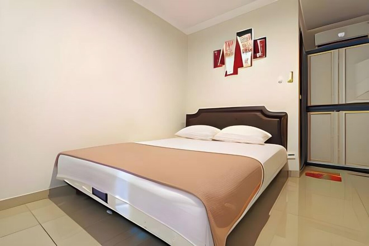 Una camera da letto ordinata con un letto, un armadio e opere d'arte appese al muro.