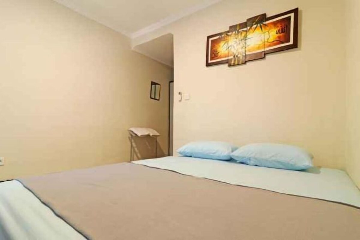 A bedroom with a bed, a chair, and a wall-mounted picture.
