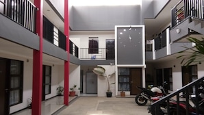 Un espace intérieur à plusieurs niveaux, doté d’un escalier central, de plantes en pot et d’une moto.