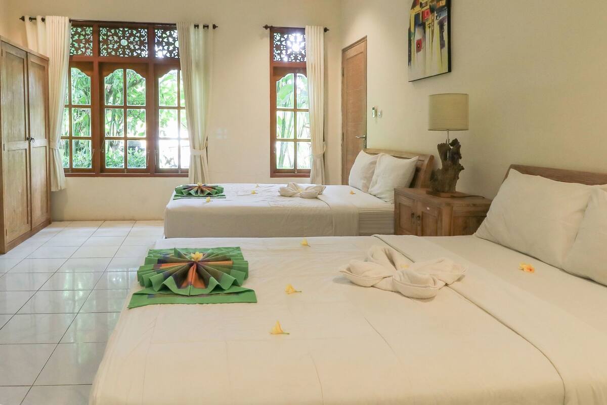 A hotel room with two beds, a wooden cabinet, a nightstand, and a painting on the wall.