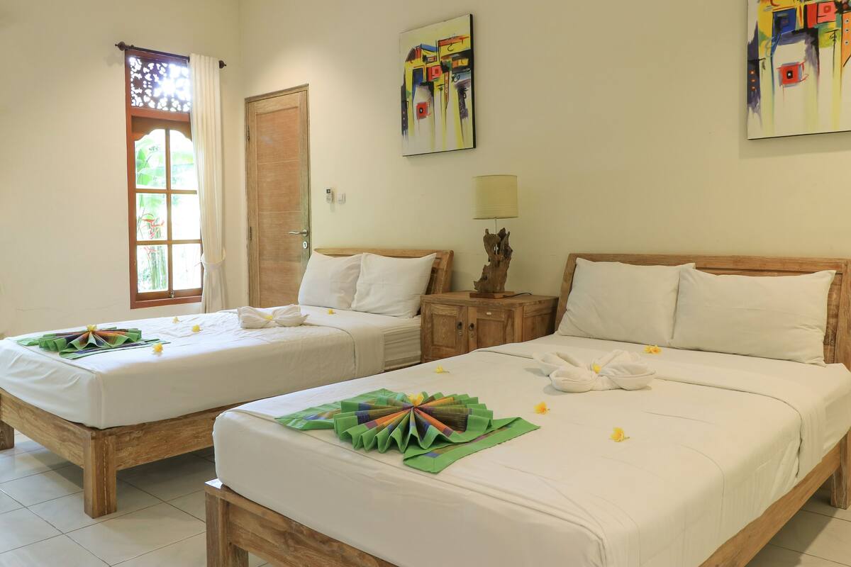 Two single beds with white linens, wooden headboards, and a wooden nightstand with a lamp between them.